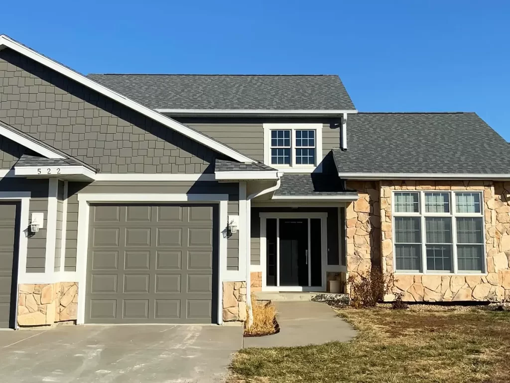 Modern home with a newly installed gray shingle roof and light stone accents for improved durability and style.