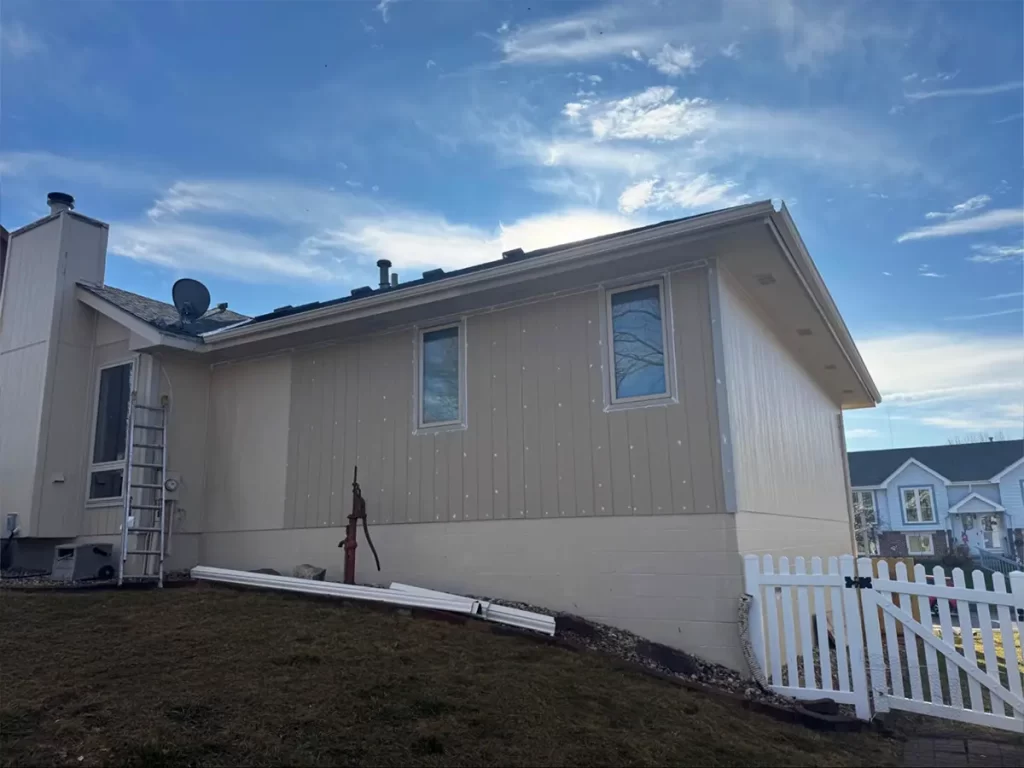 Suburban home with beige siding, minimalist design, and a spacious yard under a clear blue sky.