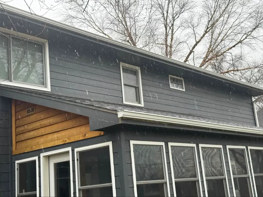 Two-story home with updated siding featuring a mix of dark gray panels and natural wood tones.