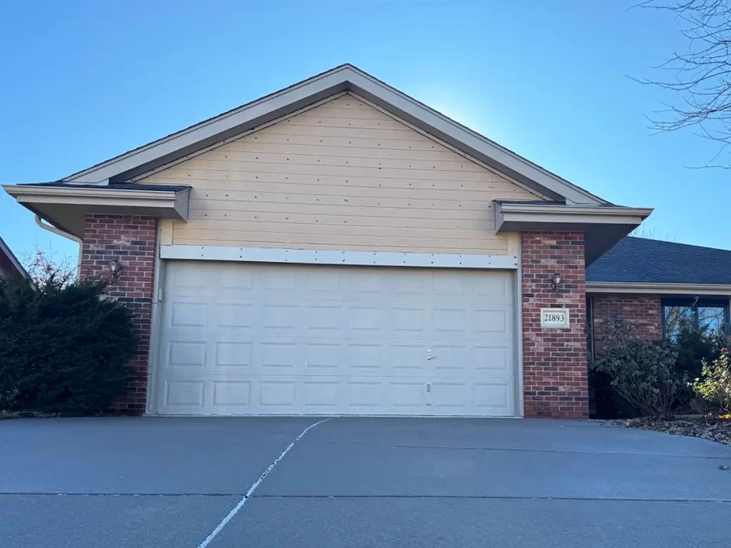 Brick and siding house with a white garage door, framed by a clean driveway and simple landscaping.