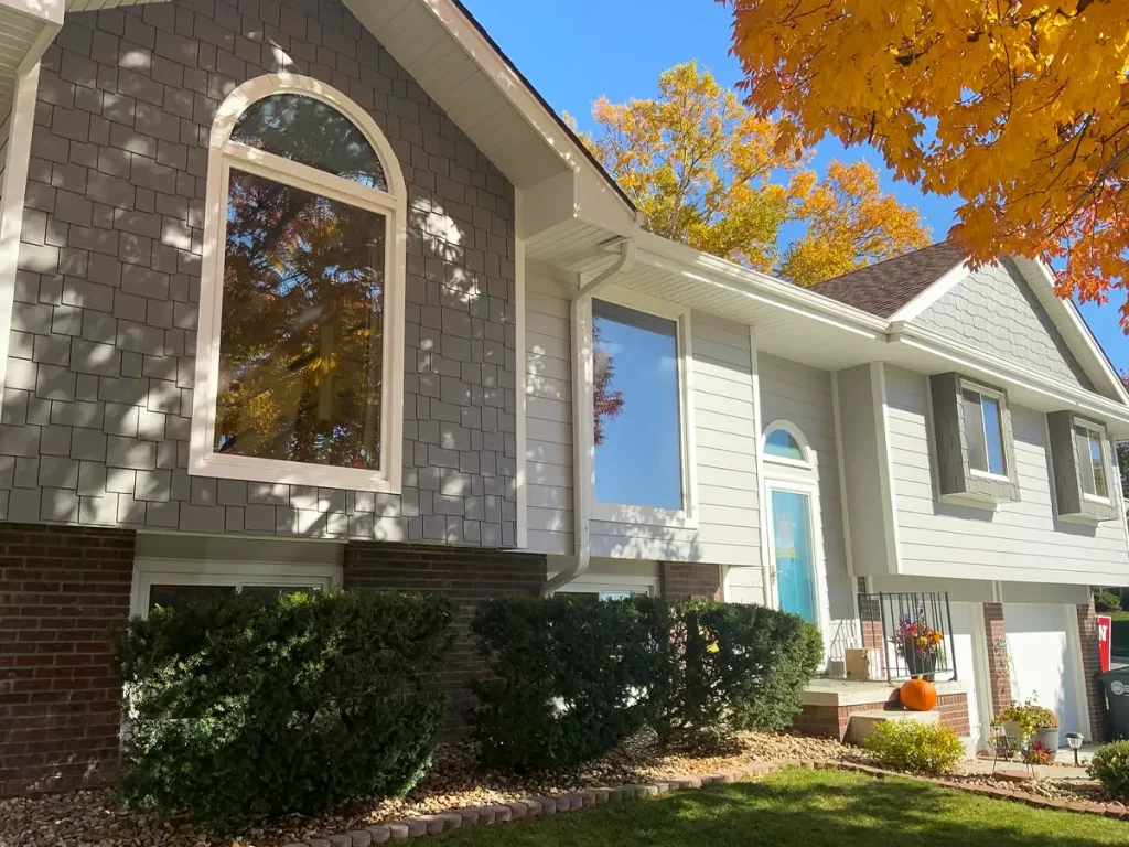 House with HardieShingle® Siding and large arched windows, surrounded by vibrant autumn foliage.