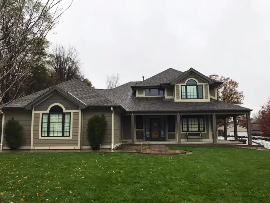 Traditional ranch-style home with light gray siding, arched windows, and a sprawling green lawn.