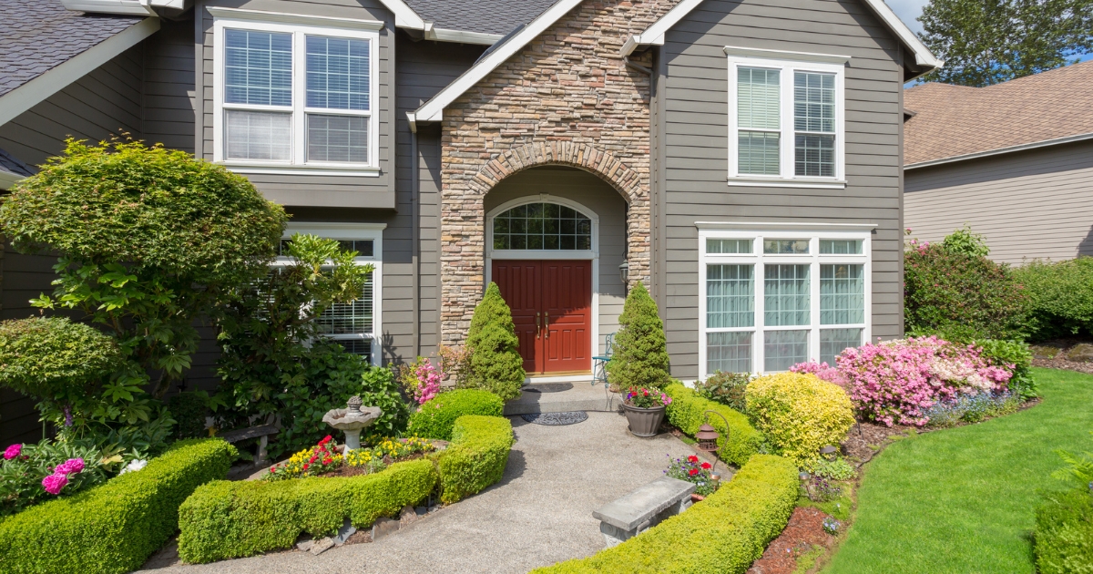 Front view of a house with stone and siding exterior, red door, and landscaped entry.