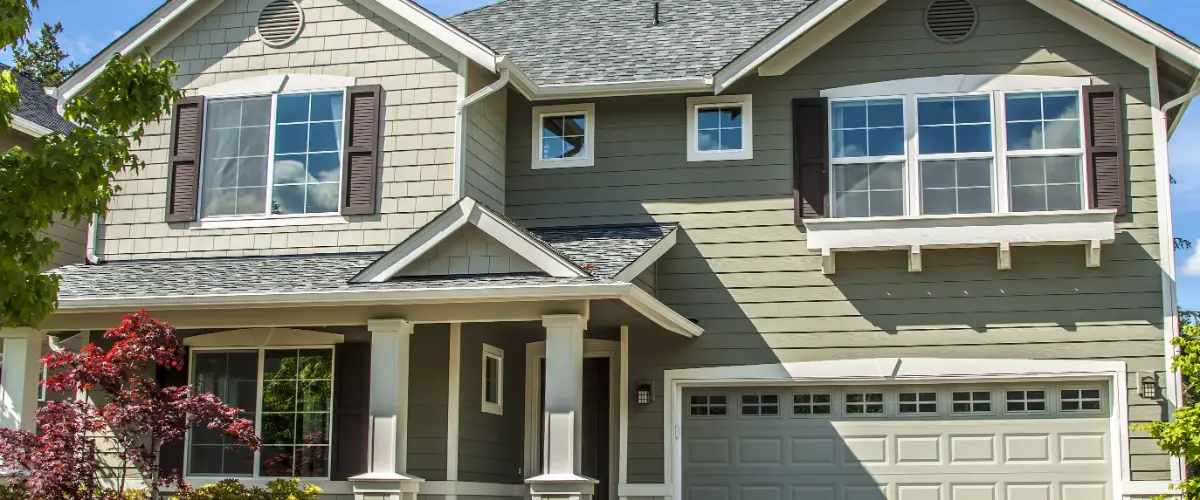 a two-story single-family home featuring sage green siding and a gabled roof design