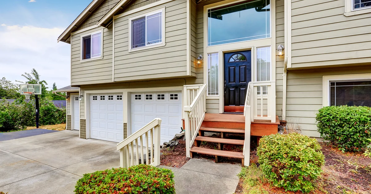 siding two story house with beige siding black front door and white garage
