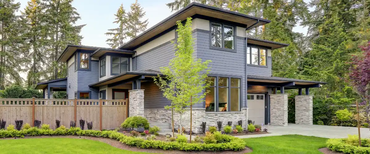 a modern house with horizontal siding in blue-gray color, with stone veneer accents on pillars and the lower portion of the front facade