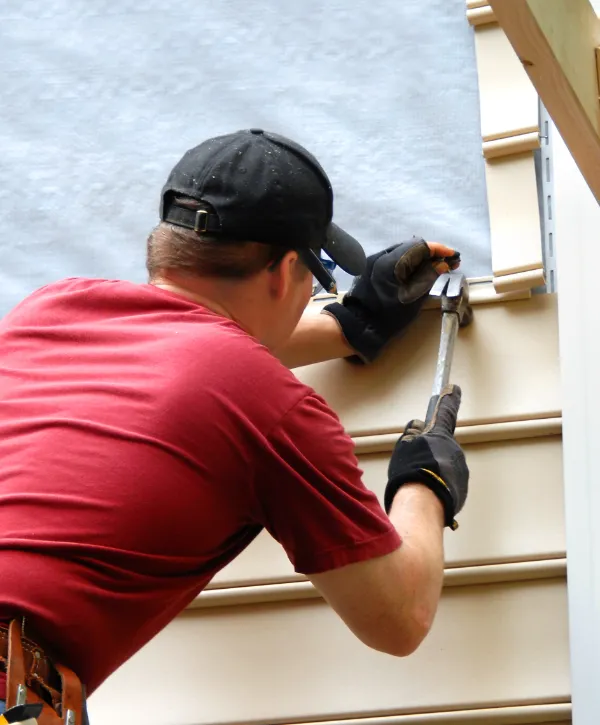 a worker installing vinyl siding on a building
