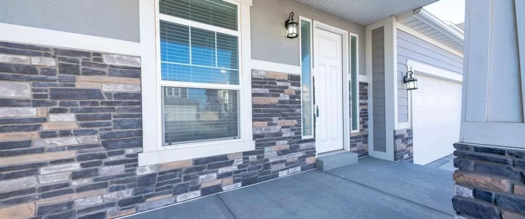 Charcoal grey panel siding used as exterior cladding combined with multi-colored stone veneer on a garage and entryway.