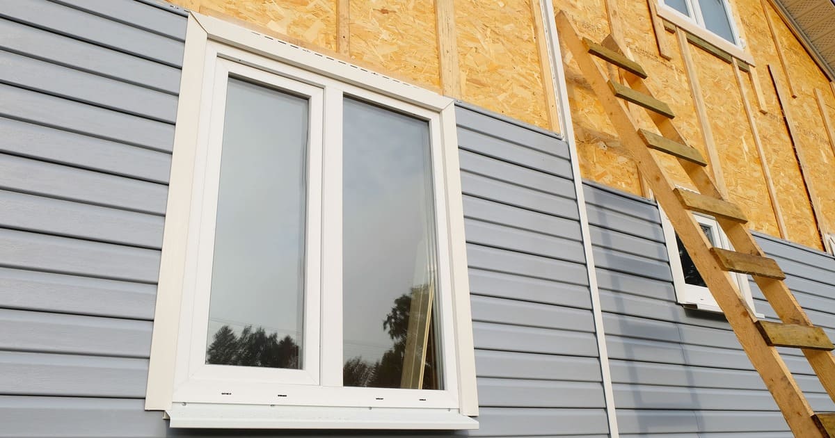 A modern home exterior featuring James Hardie panel siding in a dark grey finish paired with natural stone accents and white trim.