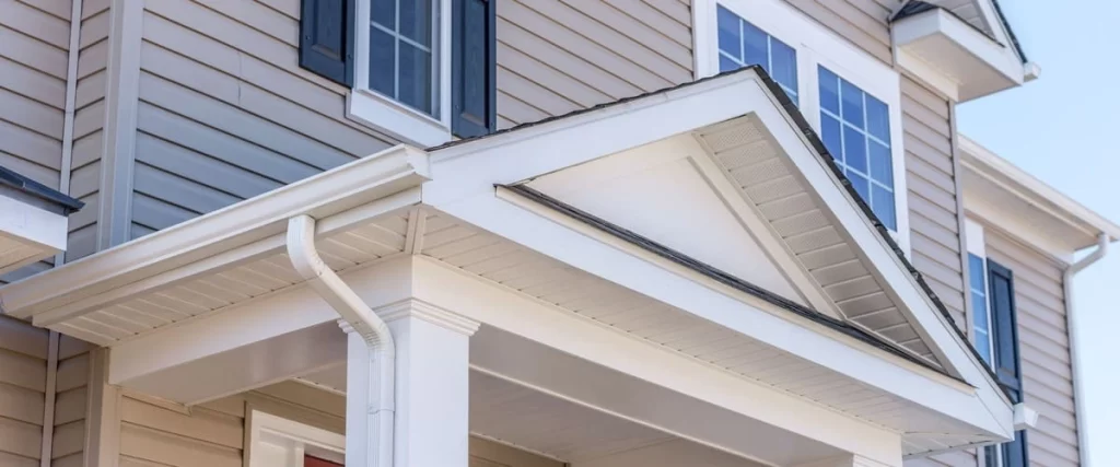Close up view of a residential home featuring clean white horizontal siding on the porch overhang and pillars with beige lap siding on the main exterior walls.