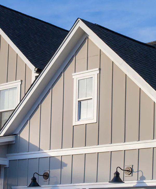 Expert siding repair in West Omaha, NE, featuring modern tan board and batten siding with white trim and exterior lighting.