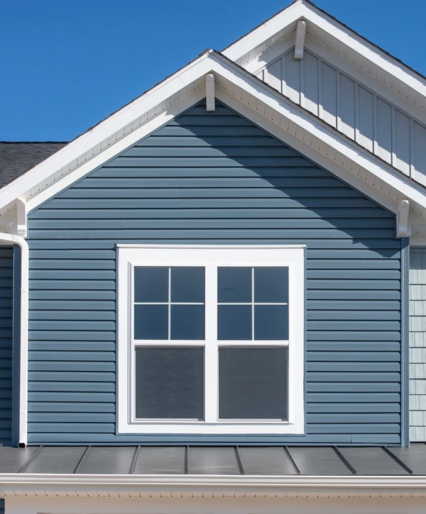 Professional siding installation in North Omaha, NE featuring deep blue horizontal lap siding with clean white window trim and gabled roof accents.