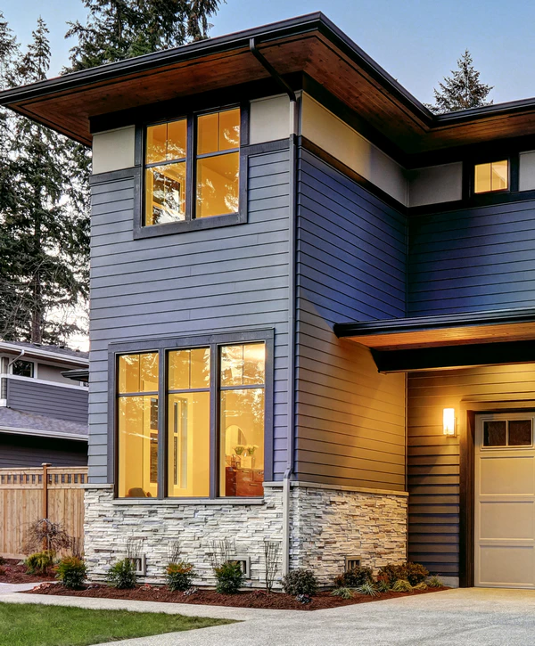Exterior view of a modern two-story home in Ralston, NE featuring blue siding, white stone veneer, and large black-framed window replacement.