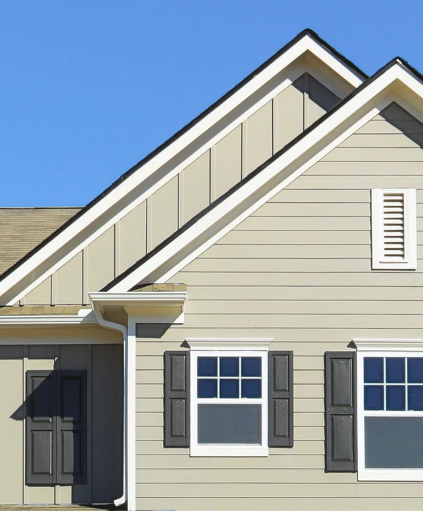 A close-up view of a completed siding installation in North Omaha, NE, featuring tan horizontal lap siding combined with vertical board and batten accents in the gable.