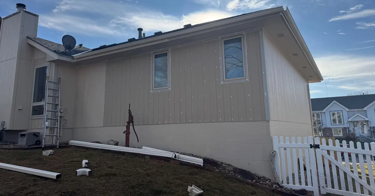 Vertical board and batten siding installation on a residential home exterior with new trim and gutters