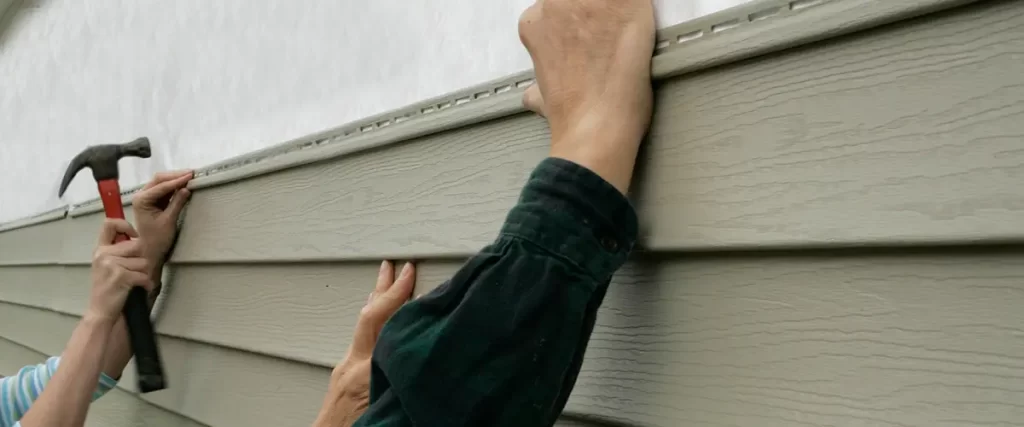Contractor installing fiber cement siding during a home exterior renovation for improved durability and curb appeal