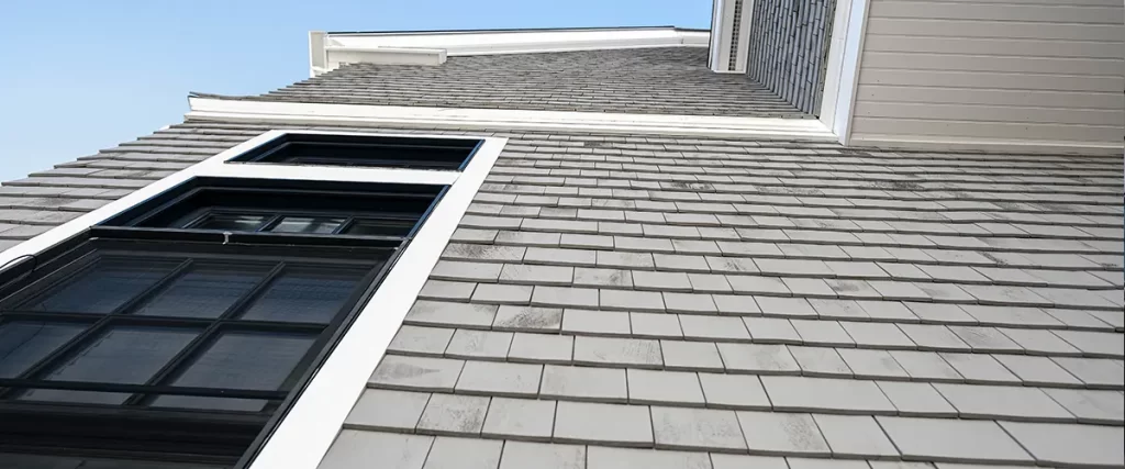 Close-up of cedar shake siding with black-framed windows on a custom home exterior.