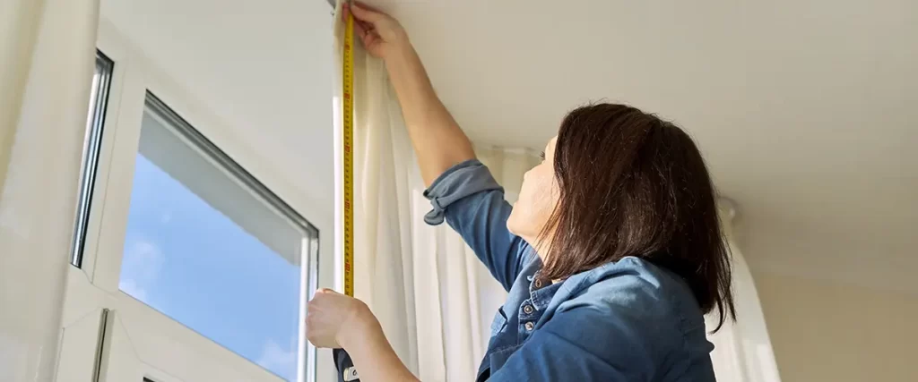 Homeowner measuring window opening for custom replacement window installation.